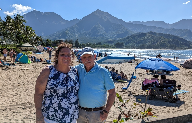family standing on a sunny sandy beach with a beautiful view of the mountains
